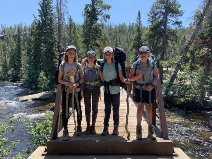 四个中学生背着书包站在山中的一座桥上